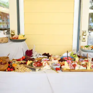 Beautifully plated up, brightly coloured gourmet wedding dishes on grazing table with pleated white tablecloth